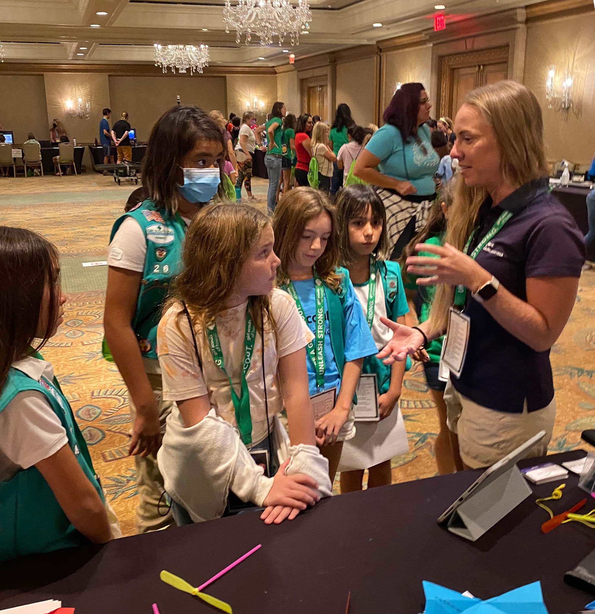 An instructor speaks to a number of girl scouts at a convention center