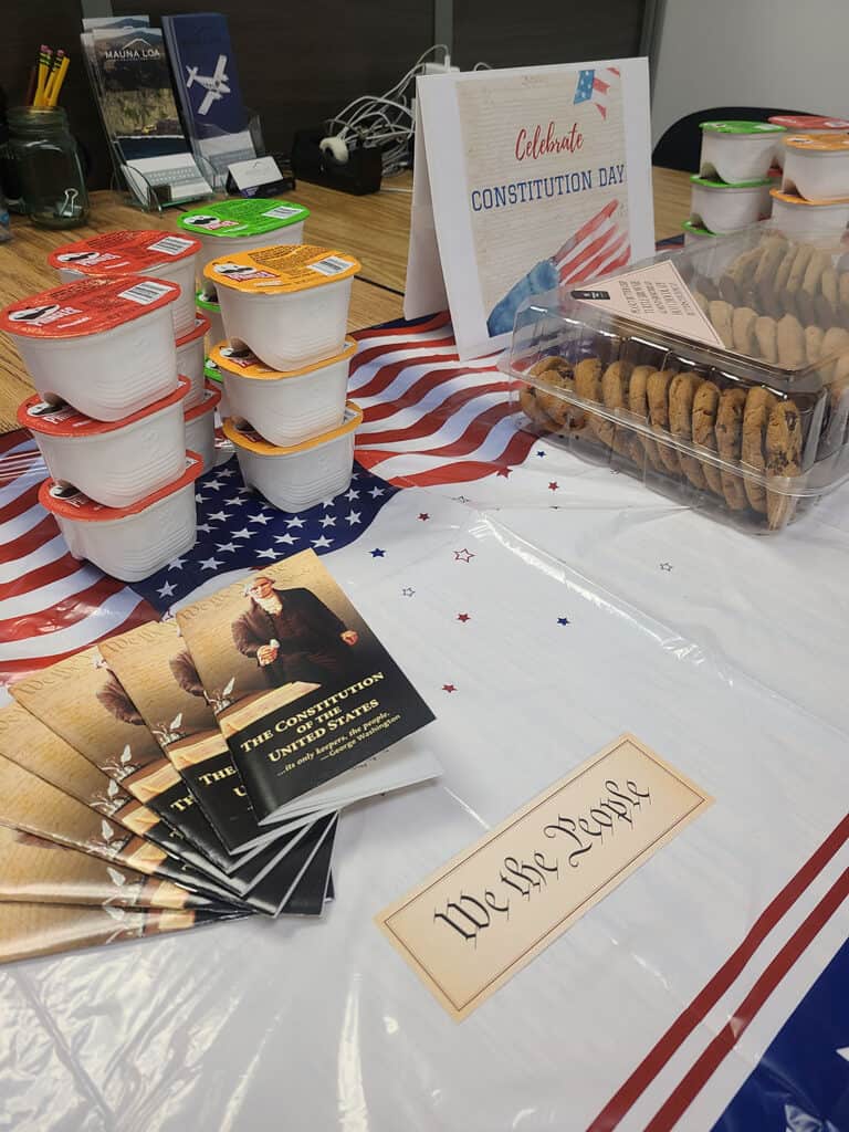 Several snacks sit out on a decorated table. There's a flyer that says "celebrate constitution day", a card that says "we the people", and several booklets titled "The Constitution of the United States" artfully displayed
