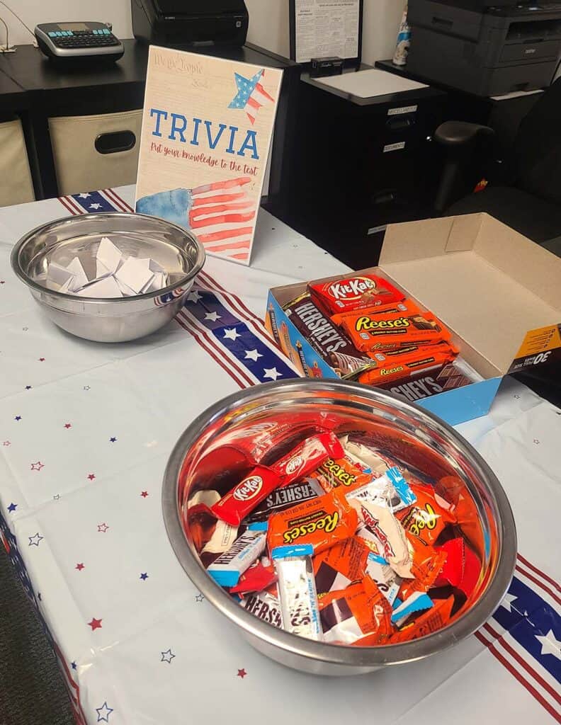 Several snacks sit out on a decorated table. There's a flyer that says "trivia" in front of a bowl full of folded cards.