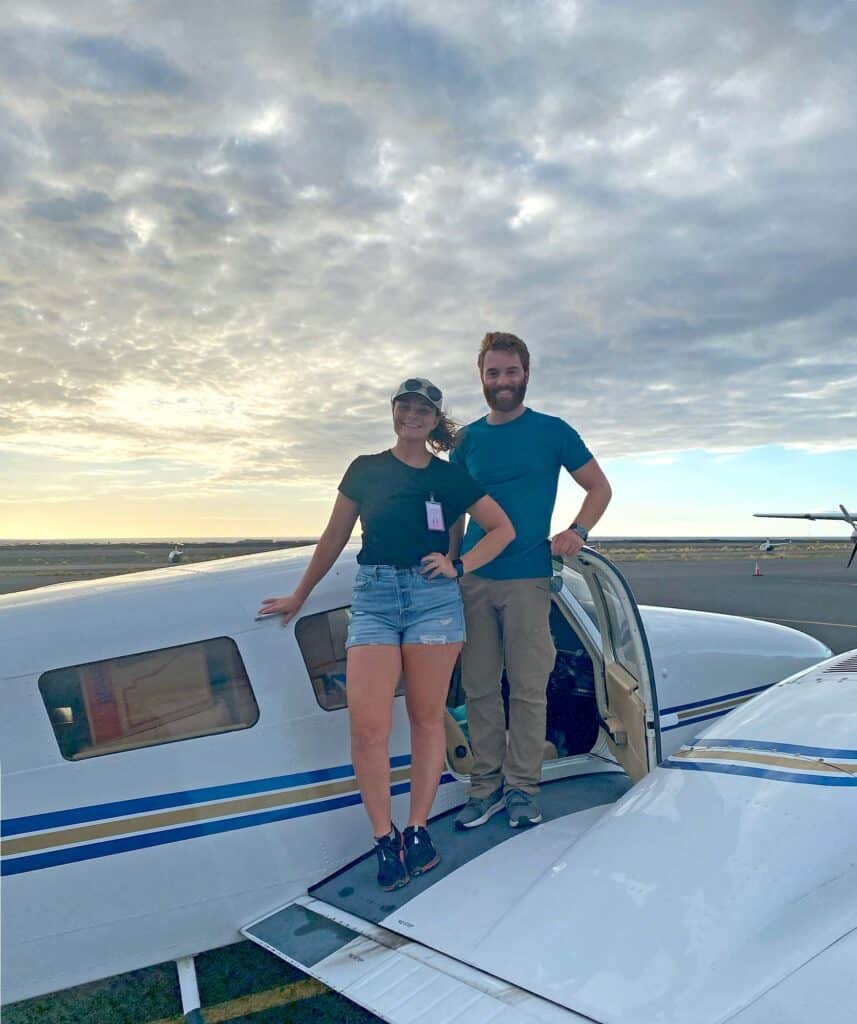 Two people stand on the wing of an airplane loaded with emergency supplies