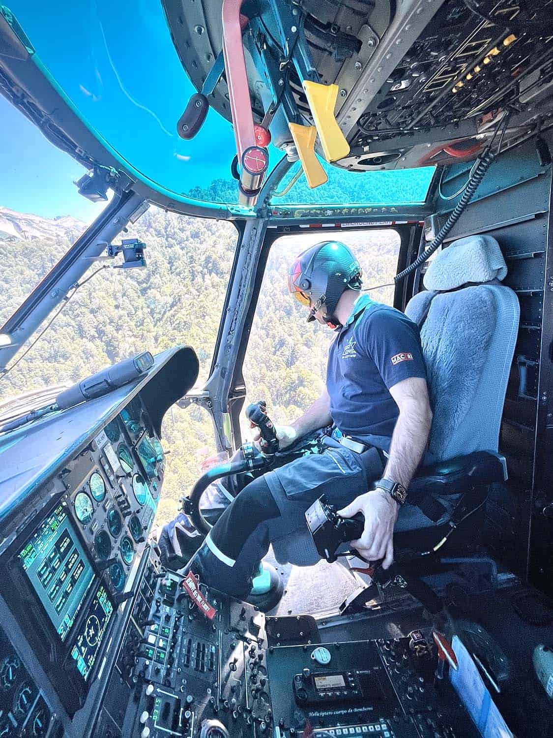 A man pilots a helicopter and looks out of the starboard window